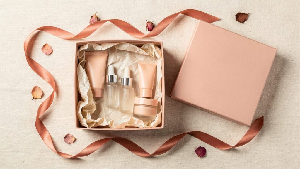 Caja de regalo rosada con cinco mini productos de skincare entre papel de seda